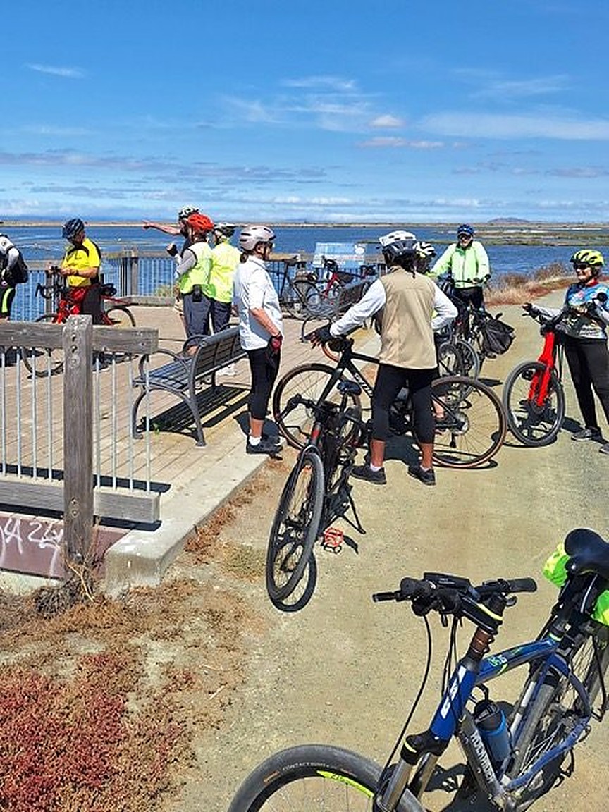 Senior Spokes riders with bikes overlooking the water